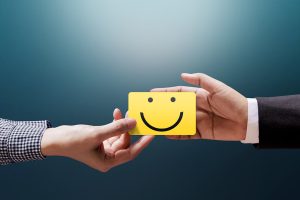 Customer giving Happy Smiley Face Card into a Hand of Businessman