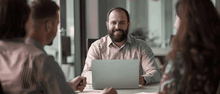 Showing the attributes of a inspirational leader - man sitting at a meeting with his team and computer.
