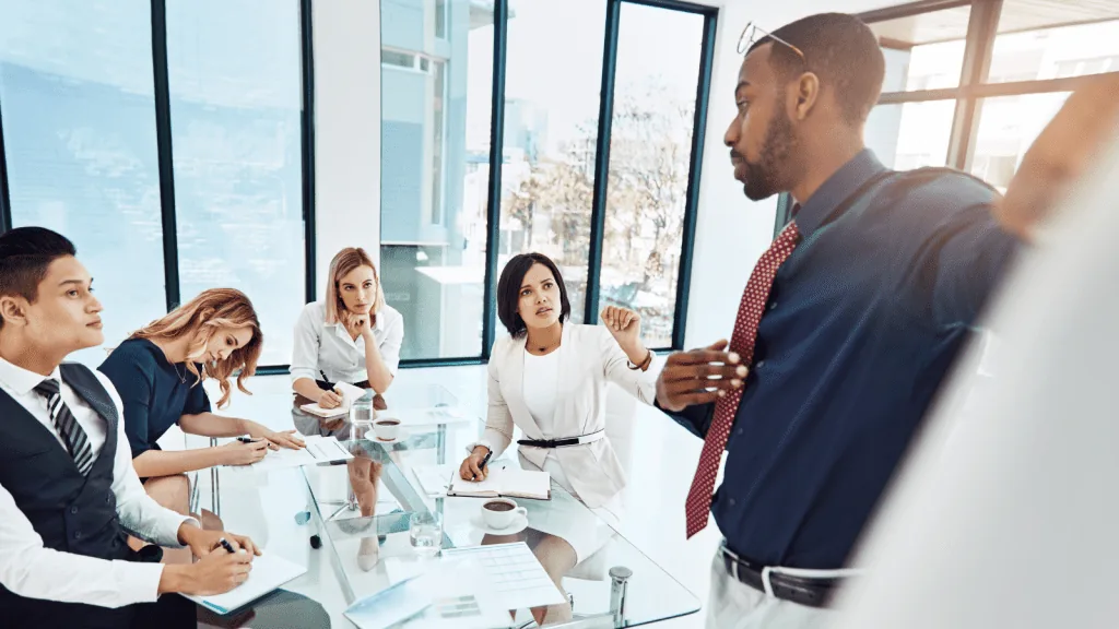 A leader is in a meeting and learning form his team by leading by listening.