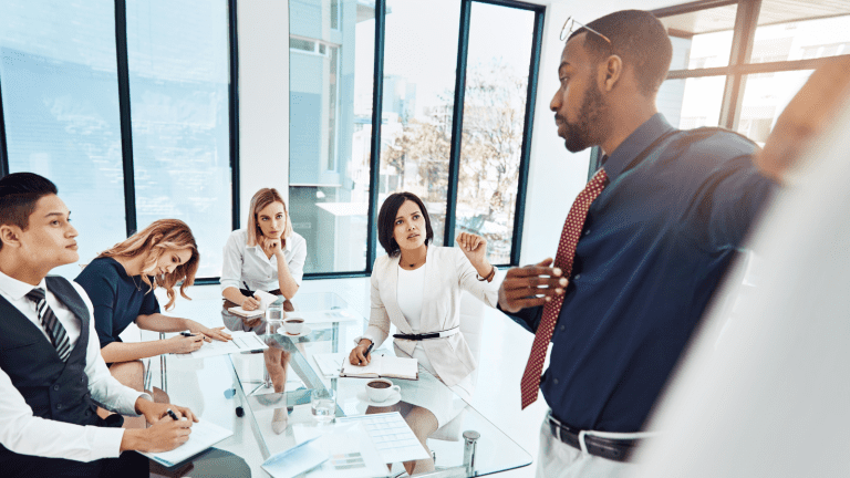 A leader is in a meeting and learning form his team by leading by listening.