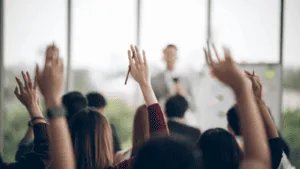 Leaders participating in a leadership development coaching session with hands raised during a group activity