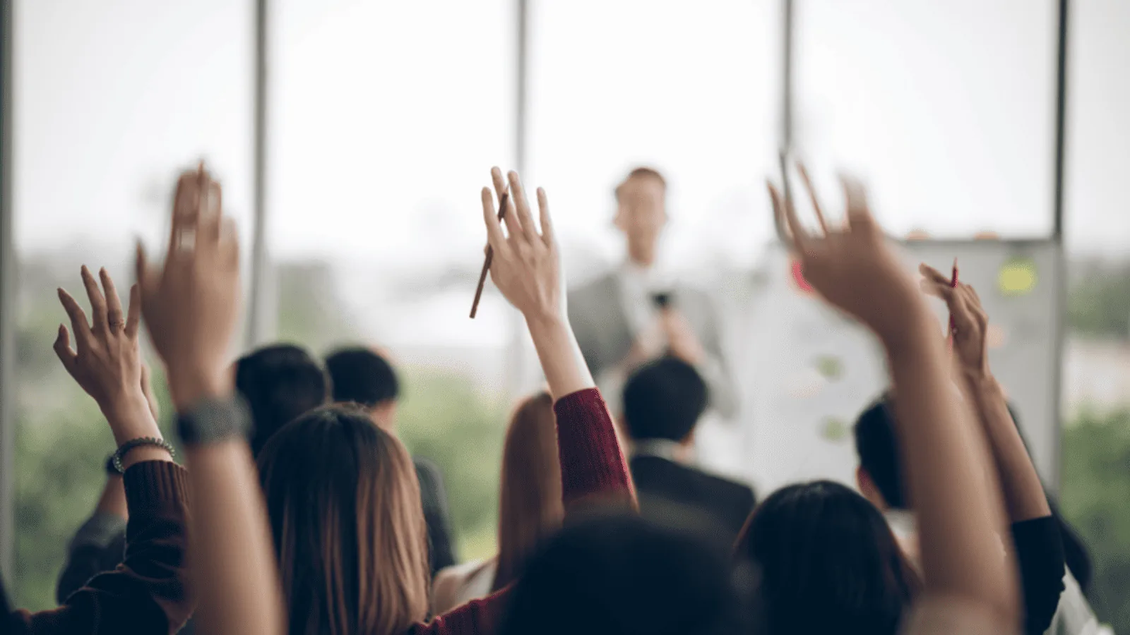 Leaders participating in a leadership development coaching session with hands raised during a group activity