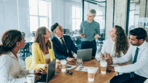 A team in a meeting using the Five Behaviors to help individuals understand how their actions influence the team's success.